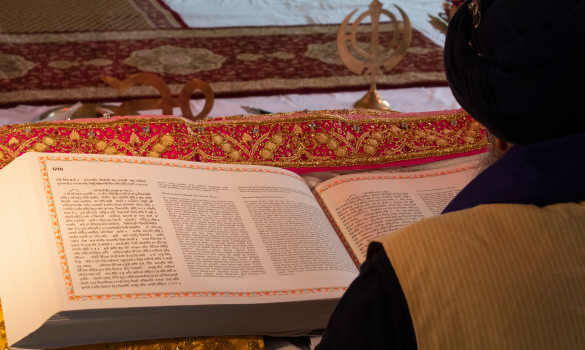 man reading siri guru Granth sahib